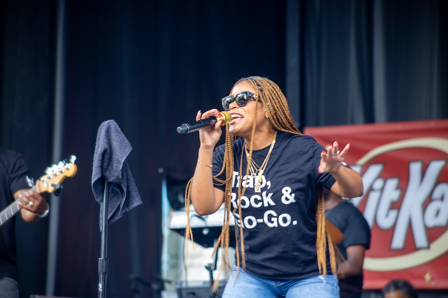 Live Performance by Black Alley: A singer from the band Black Alley performing energetically on stage, holding a microphone, with musicians in the background.