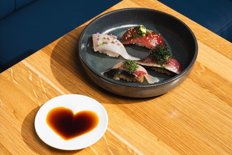 elegant plate of complex omakase sushi pieces and a small plate of soy sauce poured in the shape of a heart