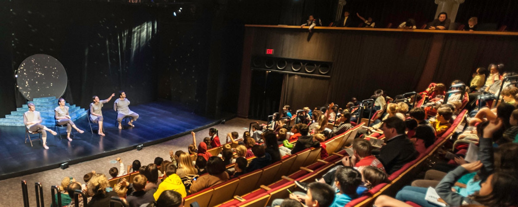 Audience watching a performance on stage with four actors.