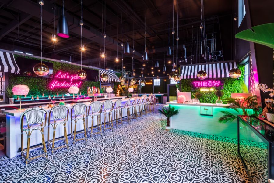 Colorful interior of Throw Social in DC with neon signs, chic bar seating, patterned tile floor, and vibrant decor.