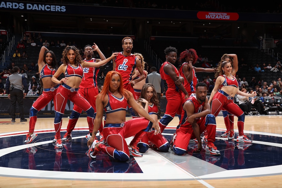 A dynamic group of dancers in red outfits performs during a Washington Wizards basketball game.