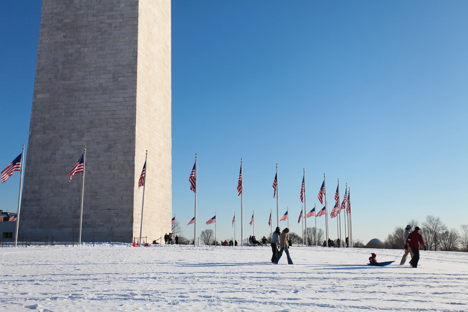 Family on snowy Washington Monument grounds on the National Mall - The best snow day activities in Washington, DC