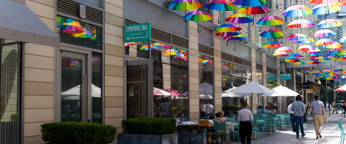Colorful umbrellas hang above the outdoor dining area of Centrolina Osteria at CityCenterDC, creating a vibrant and inviting atmosphere.