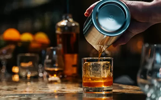 Bar tender pouring whiskey into a glass
