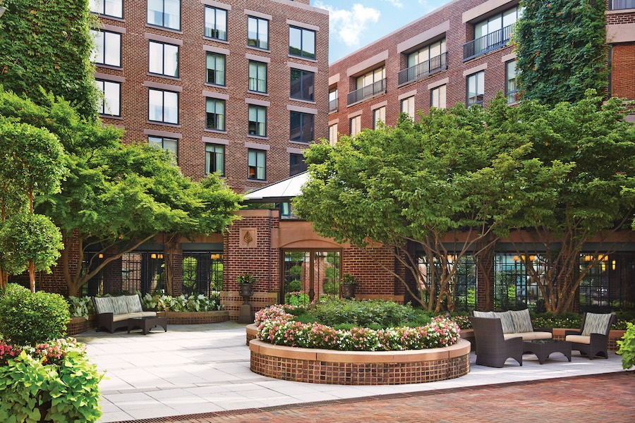 Charming hotel courtyard with lush greenery and outdoor seating.