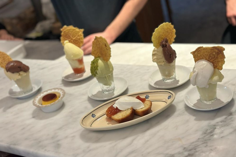 Various desserts, including ice cream with wafers and a plate of pastries with whipped cream, arranged on a marble counter.