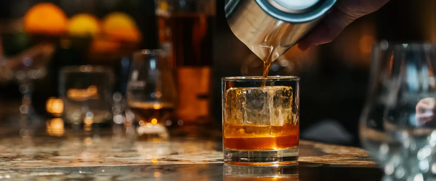 Bar tender pouring whiskey into a glass